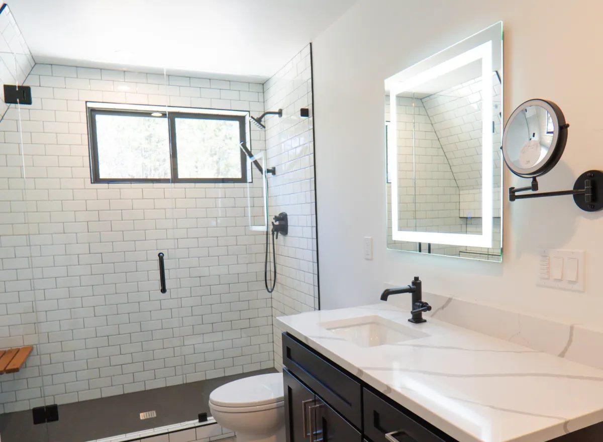 White subway tile bathroom remodel - walk-in shower with glass door, black fixtures, and new vanity